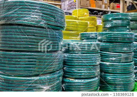 Coiled garden hoses stacked in hardware store display with colorful irrigation supplies 138369128