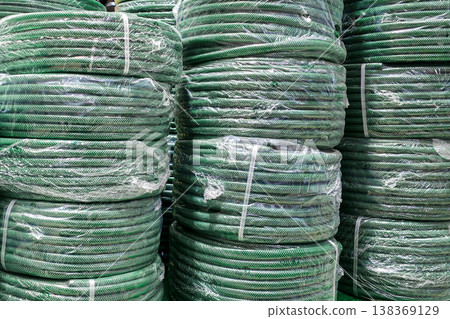 Stacks of green coiled garden hoses wrapped in plastic in hardware store warehouse display Stacks of green coiled garden hoses wrapped in plastic in hardware store warehouse display 138369129