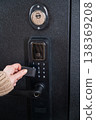 A woman opens a modern smart door lock using a contactless key. 138369208