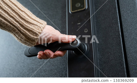 A woman opens a modern smart door lock with a digital keypad and biometric fingerprint access. A woman opens a modern smart door lock with a digital keypad and biometric fingerprint access. 138369209