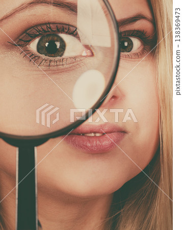 Woman looking through magnifying glass Woman looking through magnifying glass 138369473