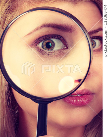 Woman looking through magnifying glass Woman looking through magnifying glass 138369474