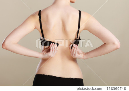 Woman dressing up her bra rear view Woman dressing up her bra rear view 138369748
