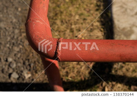 Red metal water pipe with a welded joint in an outdoor setting. Red metal water pipe with a welded joint in an outdoor setting. 138370144