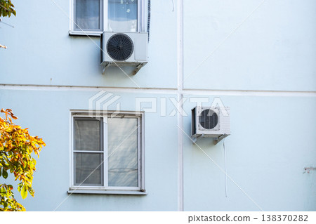 air conditioner is installed on facade of the building. air conditioner compressor is on wall. air conditioner is installed on facade of the building. air conditioner compressor is on wall. 138370282
