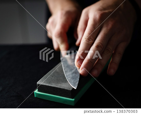 Male Hands Sharpening Kitchen Knife With Whetstone 138370303
