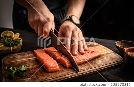 chief cutting a salmon fillet into pieces for cooking chief cutting a salmon fillet into pieces for cooking 138370315