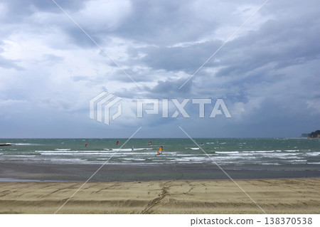 Summer scenery at Zushi Beach: People enjoying windsurfing under a cloudy sky. 138370538