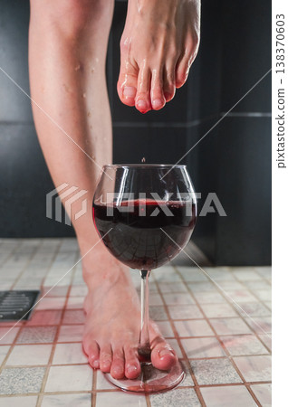 Foot fetish. A woman dips her toes in a glass of red wine. Foot fetish. A woman dips her toes in a glass of red wine. 138370603