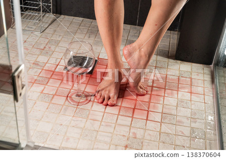 Foot fetish. A woman pours wine from a glass onto her feet in the shower. Foot fetish. A woman pours wine from a glass onto her feet in the shower. 138370604