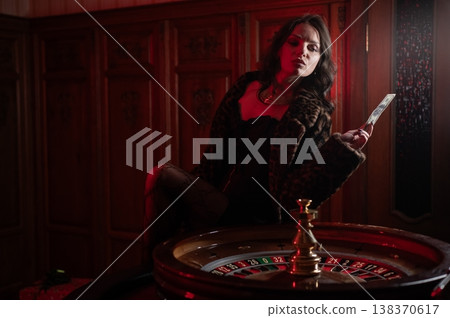 A beautiful brunette in a black dress at the casino roulette wheel. A beautiful brunette in a black dress at the casino roulette wheel. 138370617