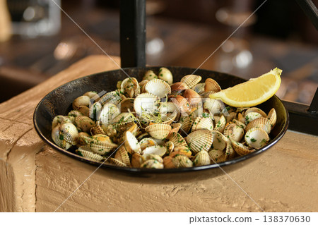 Fresh clams with herbs and lemon served in rustic plate 138370630