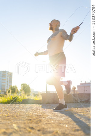 Tattooed man jumping rope during outdoor workout outdoors Tattooed man jumping rope during outdoor workout outdoors 138370794