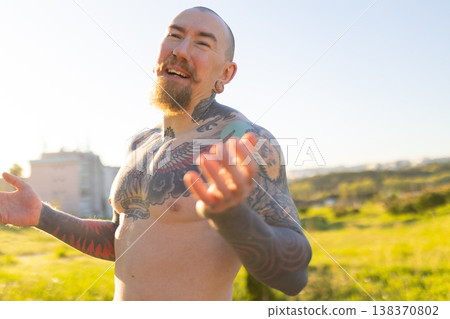Happy tattooed man laughing outdoors in sunlight 138370802