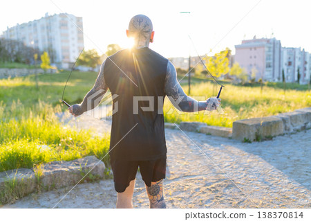 Man with full body tattoos doing skipping rope workout Man with full body tattoos doing skipping rope workout 138370814
