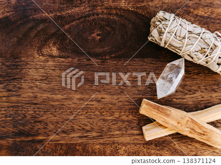 Palo santo sticks, white sage bundle and clear quartz crystal on wooden background 138371124
