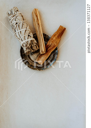 White sage bundle and palo santo sticks in metal dish on white background 138371127
