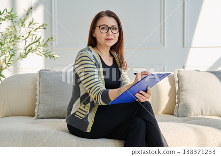 Portrait of professional psychologist therapist woman taking notes on clipboard in office Portrait of professional psychologist therapist woman taking notes on clipboard in office 138371233