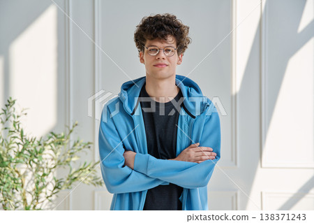Portrait of handsome young man with curly hair with crossed arms 138371243
