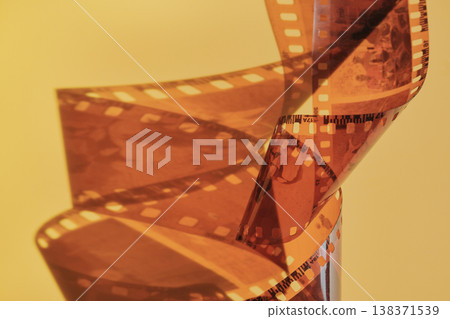 Film strip spiraling creating an abstract shape against warm background Film strip spiraling creating an abstract shape against warm background 138371539