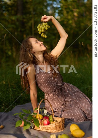 Woman playful tasting grapes in outdoor setting Woman playful tasting grapes in outdoor setting 138372192