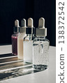 Cosmetic dropper bottles displaying clear, white and pink serums on white surface with shadows 138372542
