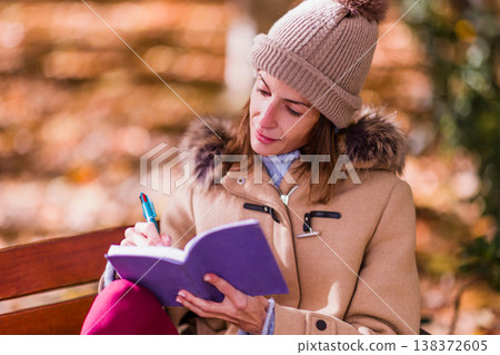Woman writing personal diary for mental health support outdoors 138372605