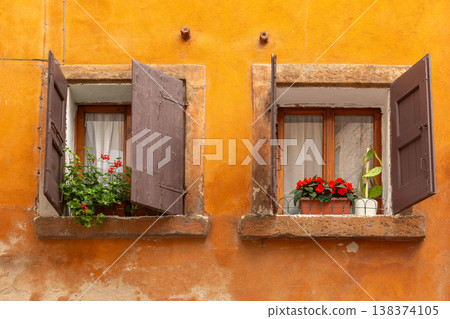 Two old windows with flowers on orange facade in Verona, Italy Two old windows with flowers on orange facade in Verona, Italy 138374105