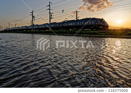 A JR Nagasaki Line express train travels across the Saga Plain at dusk, with rice paddies filled to the brim with water. A JR Nagasaki Line express train travels across the Saga Plain at dusk, with rice paddies filled to the brim with water. 138375008