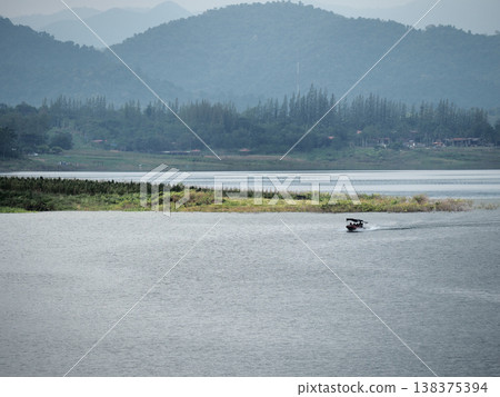 Serene lake small boat mountain landscape cloudy sky forest shoreline tranquil water Serene lake with small boat crosses Serene lake small boat mountain landscape cloudy sky forest shoreline tranquil water Serene lake with small boat crosses 138375394