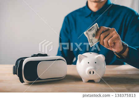 Piggy bank save future metaverse virtual digital technology reality vr, man puts cash money into ceramic bank next to headset for long term investment and online finance growth 138375813