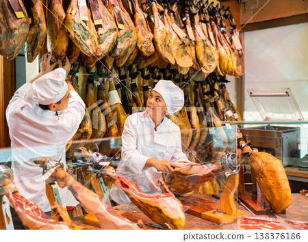 Young man and woman selling spanish jamon at counter Young man and woman selling spanish jamon at counter 138376186