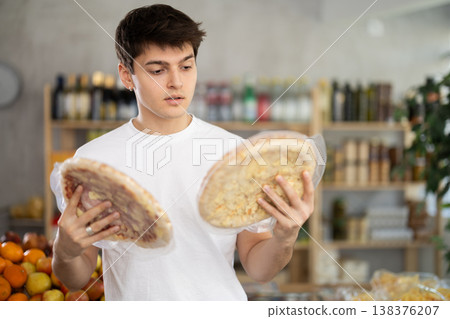 European guy looks at product and shop around, choose and buy pizza with different filling in shop 138376207