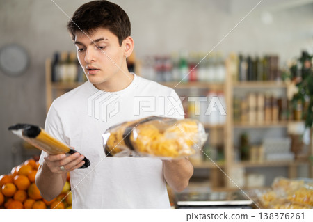 Interested young customer selecting pasta for dinner in supermarket Interested young customer selecting pasta for dinner in supermarket 138376261