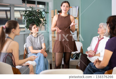 Young female speaker address to member of community, woman standing next to seated audience 138376266