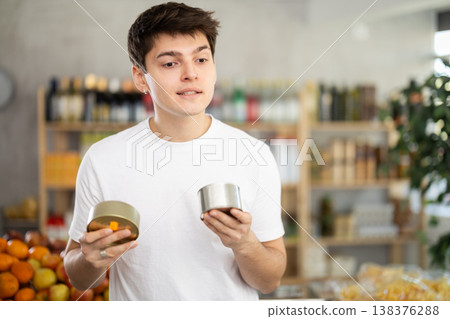 Shopping in produce supermarket - male buyer makes choice when buying canned products Shopping in produce supermarket - male buyer makes choice when buying canned products 138376288