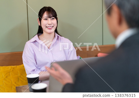 Men and women having a meeting using a computer in a cafe 138376315