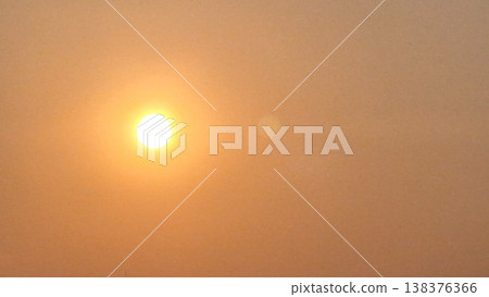 Abstract cinematic background of a bright sun glowing through heavy haze with soft warm orange tones. 138376366