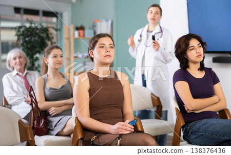 Group of women watching presentation with doctor in background Group of women watching presentation with doctor in background 138376436