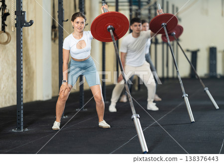Young woman training with barbell with one arm Young woman training with barbell with one arm 138376443