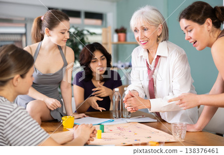 Emotional female colleagues of business company different ages playing exciting board game in office Emotional female colleagues of business company different ages playing exciting board game in office 138376461