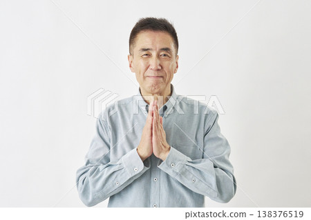 A man praying against a white background, looking directly at the camera. A man praying against a white background, looking directly at the camera. 138376519