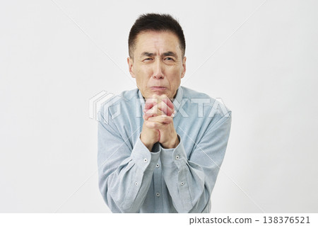 A man praying against a white background, looking directly at the camera. A man praying against a white background, looking directly at the camera. 138376521