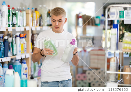 Positive young man choosing liquid detergent at household goods in store 138376563