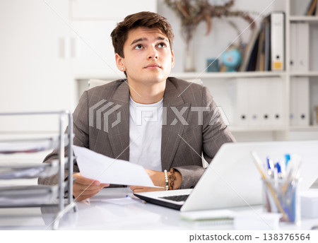 Male bookkeeper doing paperwork in workplace in office - checks accounting documents Male bookkeeper doing paperwork in workplace in office - checks accounting documents 138376564