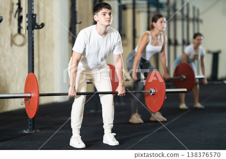 Young guy doing exercises with a barbell in gym Young guy doing exercises with a barbell in gym 138376570