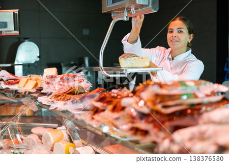 Young woman weighing cheese at counter Young woman weighing cheese at counter 138376580