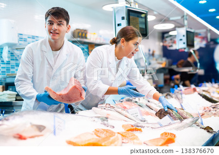 Male seller demonstrates large piece of tuna fillet at fish market Male seller demonstrates large piece of tuna fillet at fish market 138376670