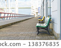Vibrant multicolored wooden benches arranged in a row along a paved waterfront walkway in Tokyo. Scenic promenade view featuring Rainbow Bridge and a modern building under a bright daytime sky. 138376835