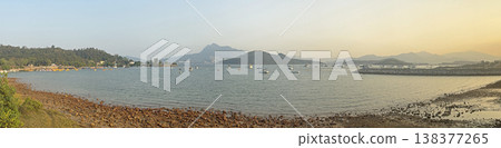 Panoramic view of a tranquil bay with sailboats and distant mountains at sunset Panoramic view of a tranquil bay with sailboats and distant mountains at sunset 138377265